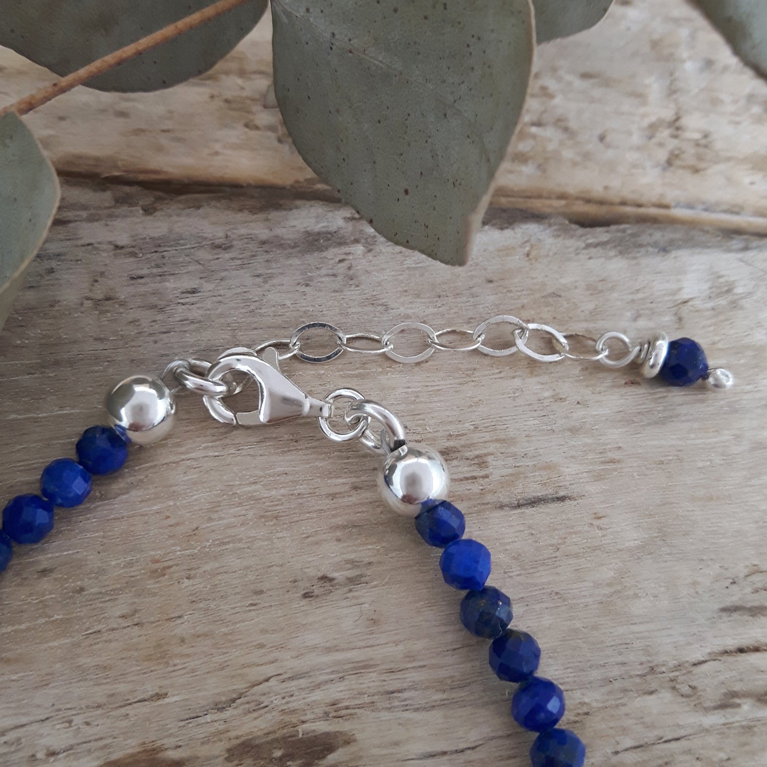 Sterling silver birthstone bracelet with blue lapis beads on a wooden surface