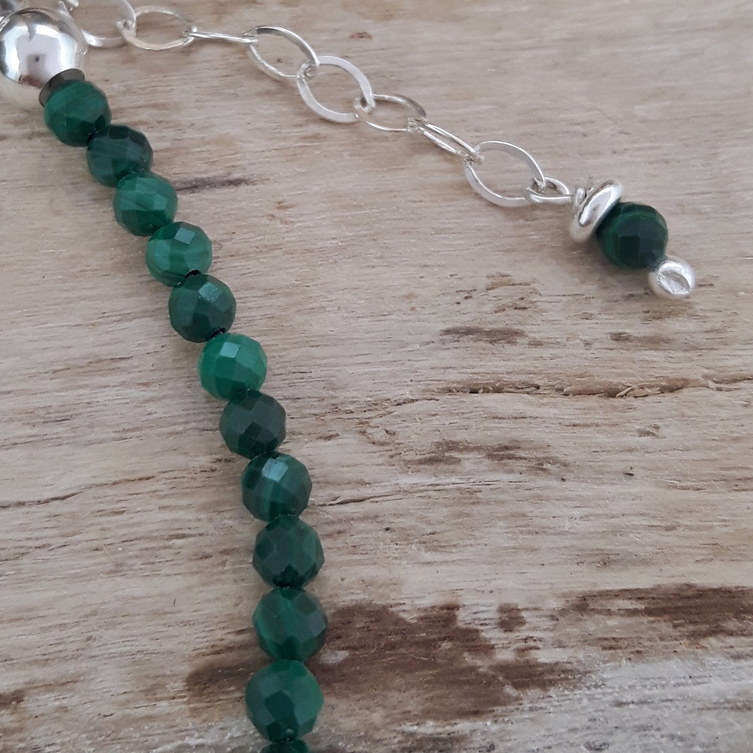 Malachite beaded bracelet with sterling silver clasp on a wooden surface
