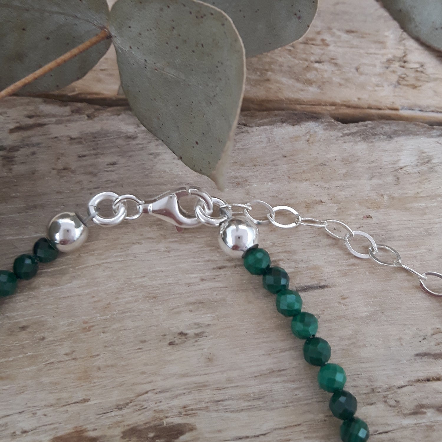 Silver bracelet with malachite beads on a wooden surface