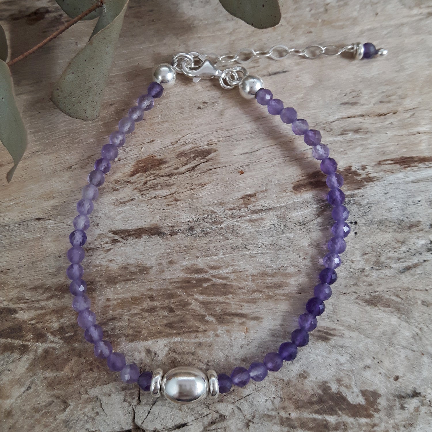 Amethyst beaded bracelet with silver clasp on a wooden surface