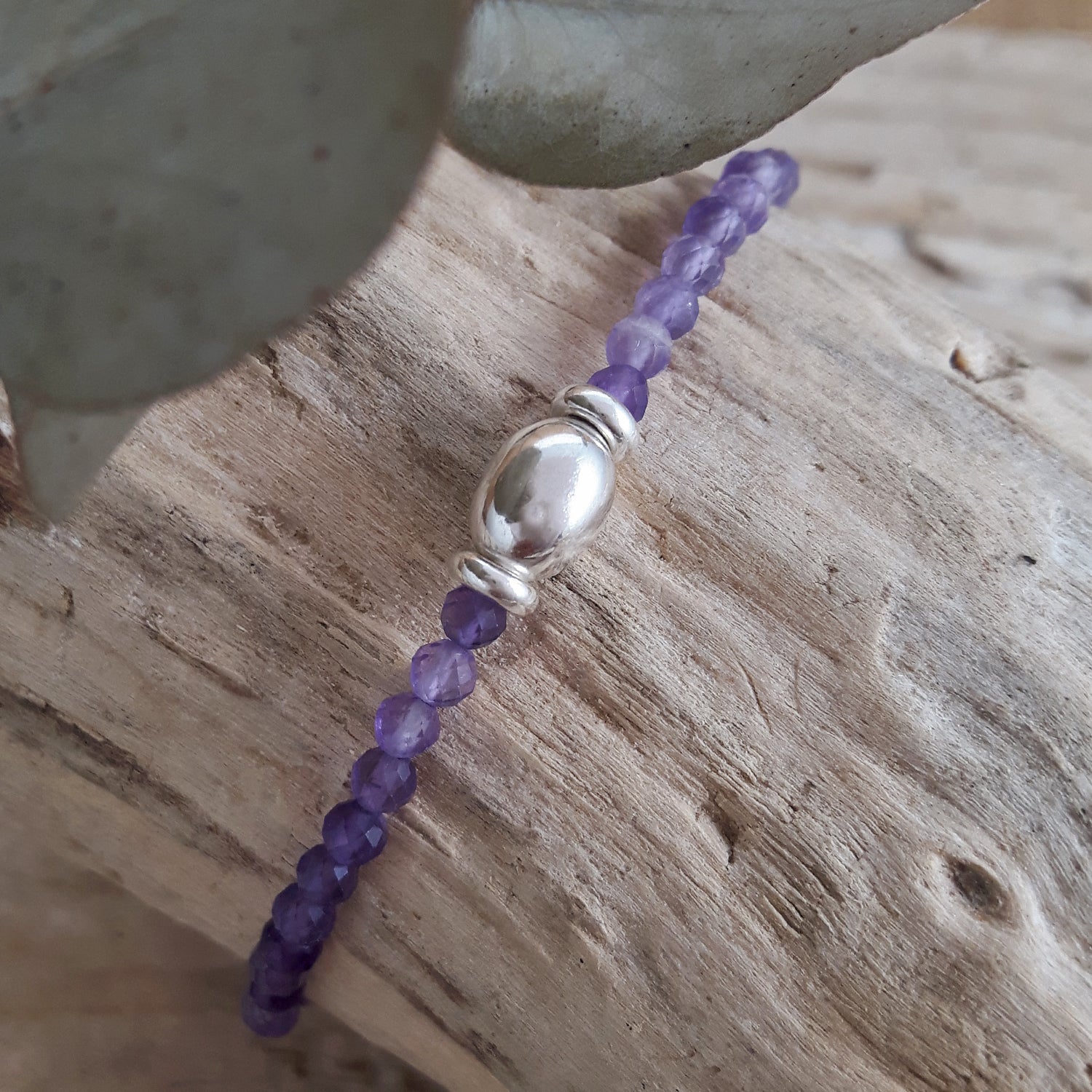 Amethyst beaded bracelet with a silver clasp on a wooden surface