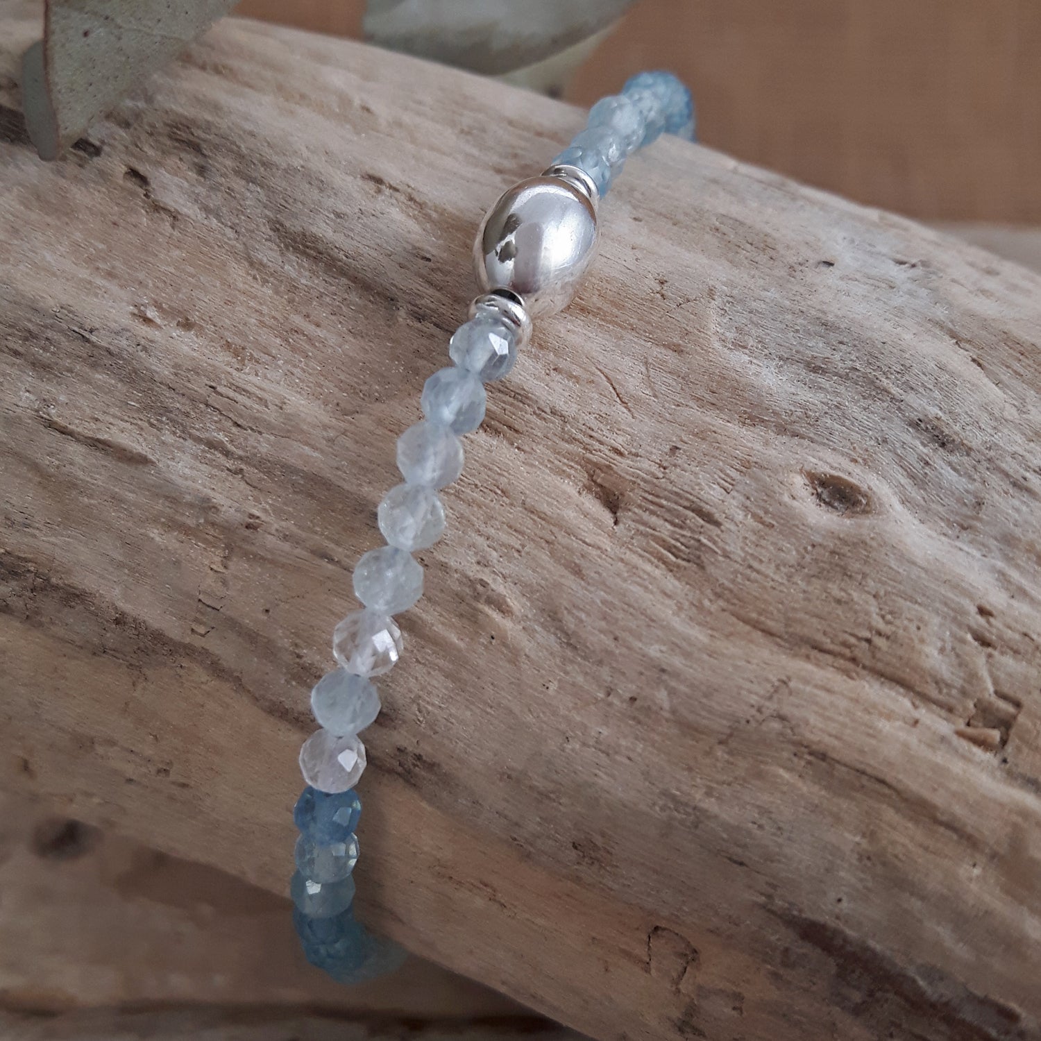 Aquamarine beaded bracelet with a silver clasp on a wooden surface
