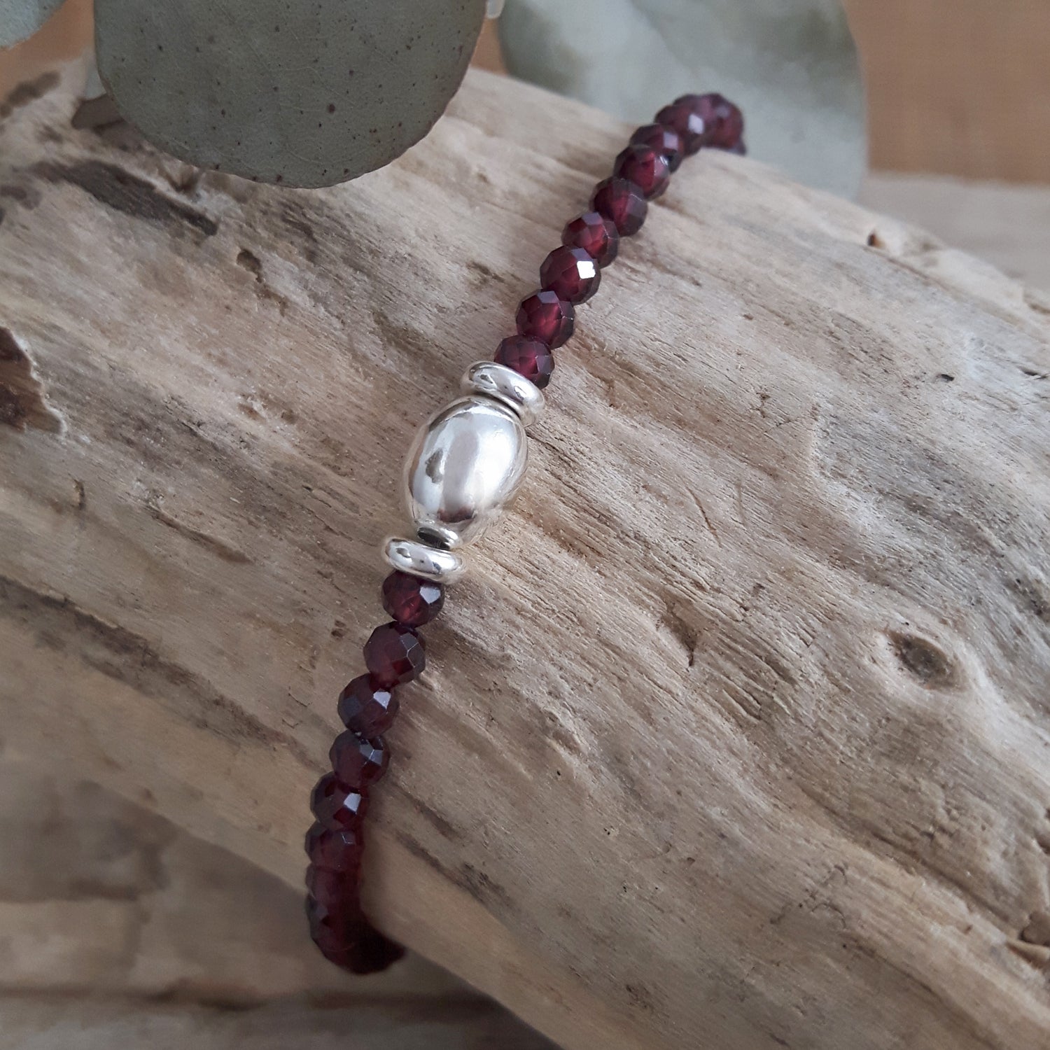 Garnet beaded bracelet with a silver clasp on a wooden surface
