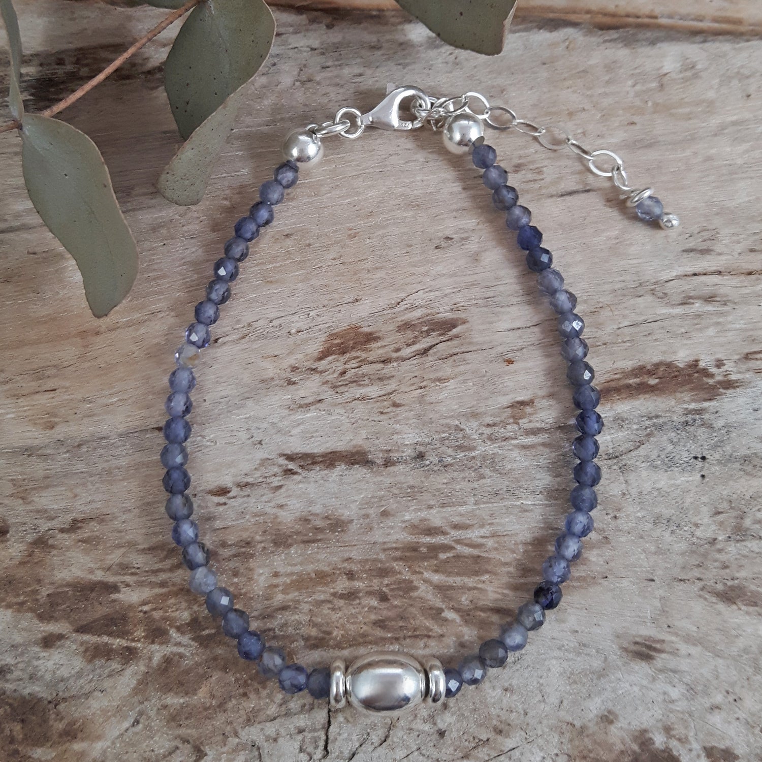 Sterling silver bracelet with blue Iolite gemstone beads on a wooden surface