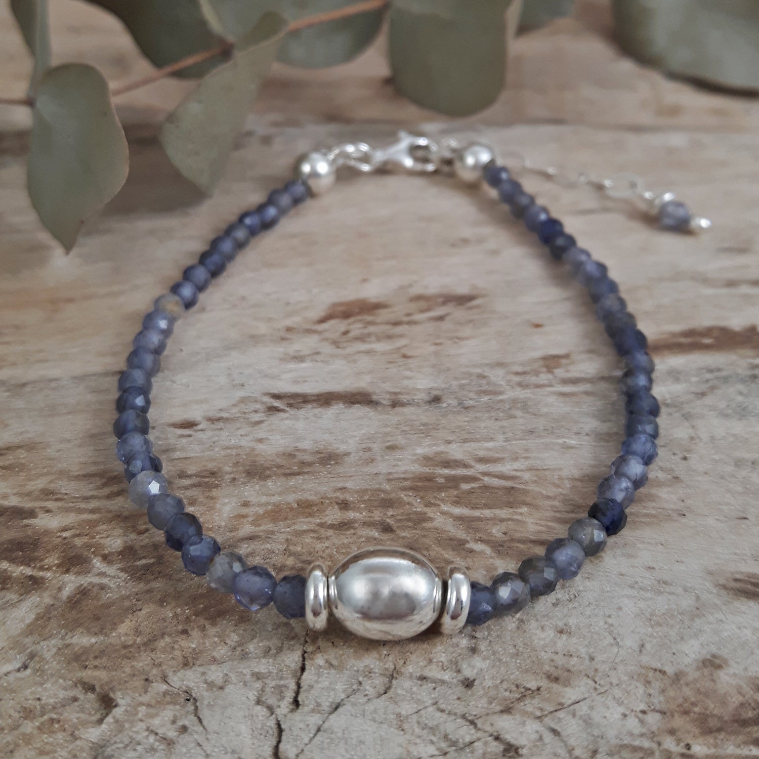 Iolite beaded birthstone bracelet with sterling silver clasp on a wooden surface