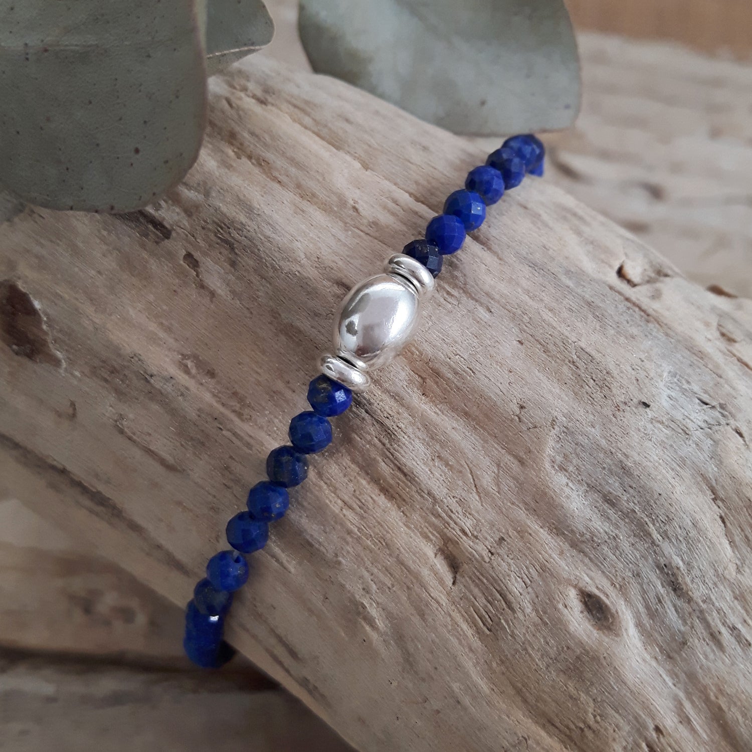 Blue lapis beaded birthstone bracelet with a sterling silver beaad on a wooden surface