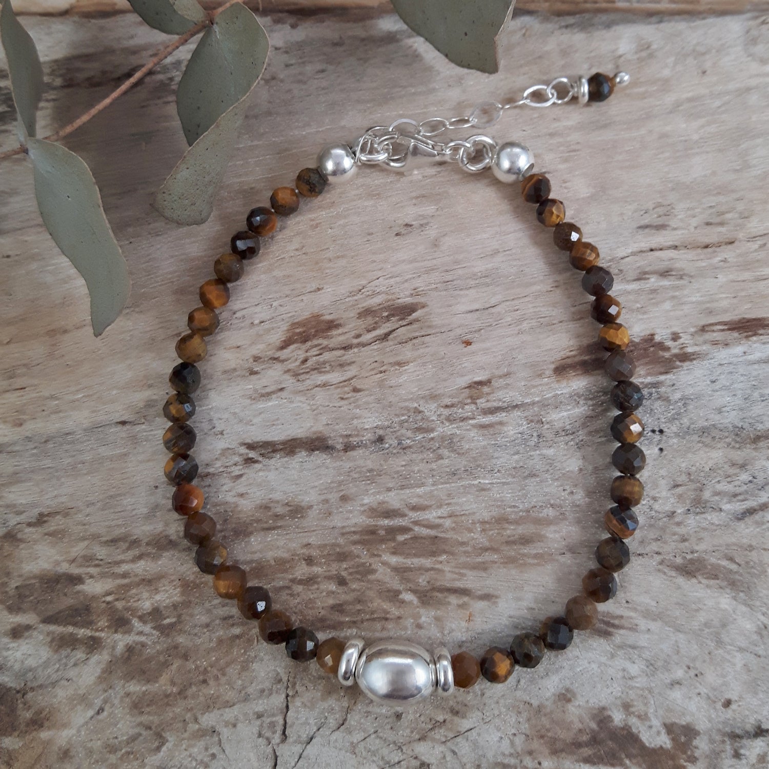 Tiger's Eye beaded birthstone bracelet with sterling silver detail on a wooden surface