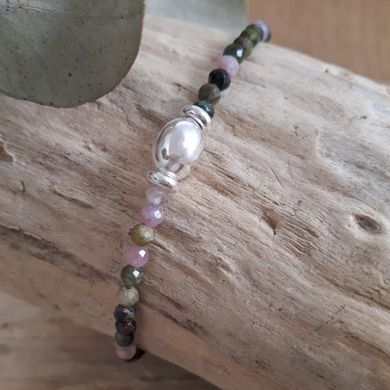 Gemstone beaded birthstone bracelet with tourmaline on a wooden surface