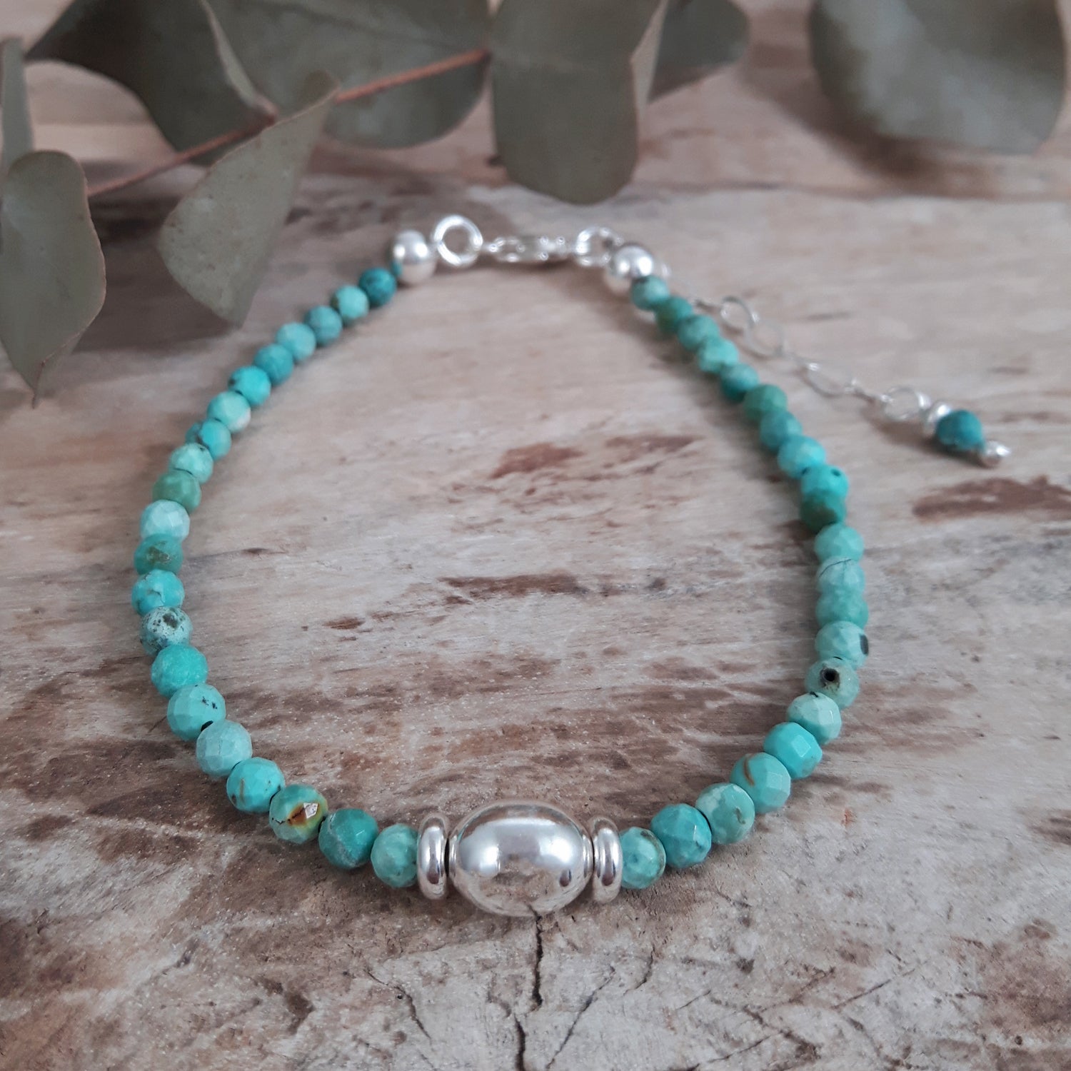 Turquoise beaded bracelet with sterling silver accents on a wooden surface