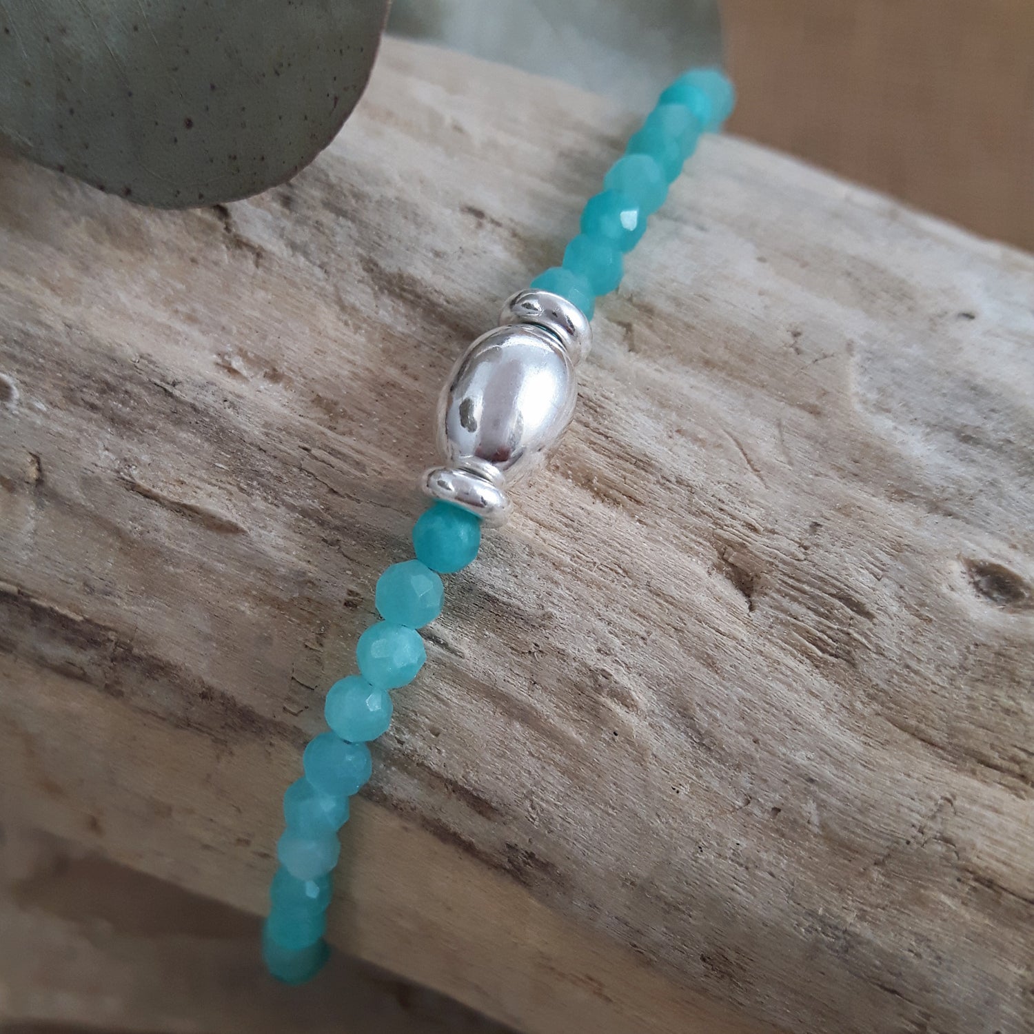 Amazonite beaded bracelet with a sterling silver orb on a wooden surface