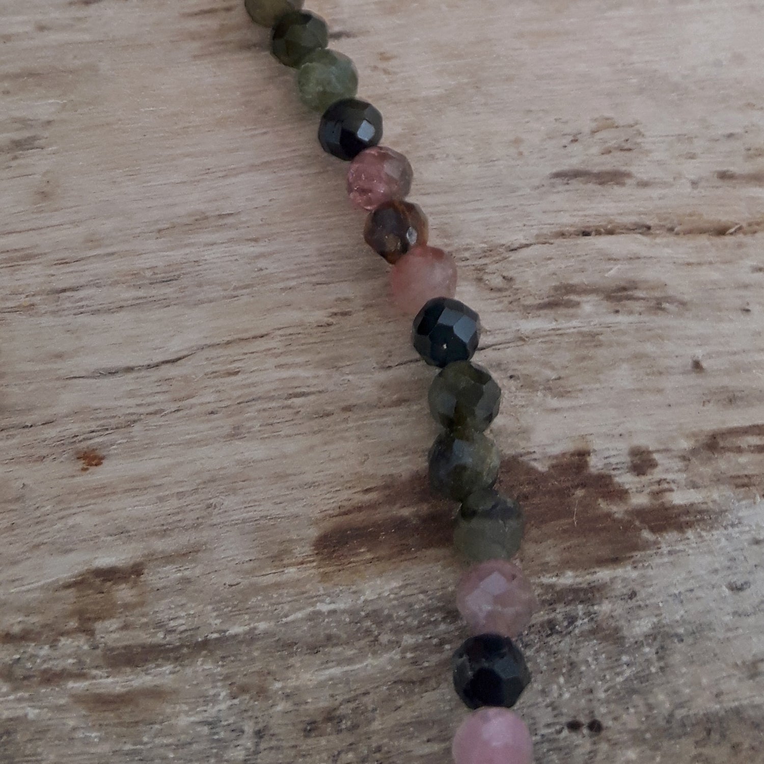 Tourmaline beaded bracelet with multicoloured gemstone beads on a wooden surface