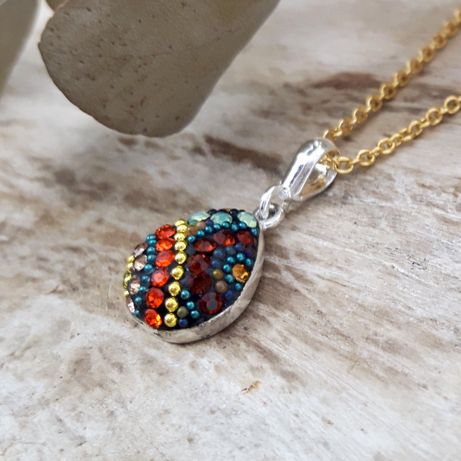 Gold-plated chain necklace with a colourful Allerga bohemian-style pendant on a wooden surface