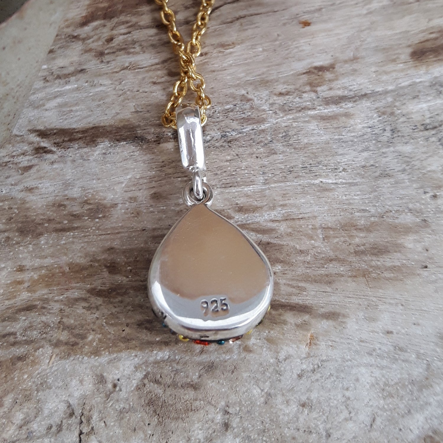 Allegra California Dream Teardrop Mini pendant back view showing a silver teardrop pendant on a gold chain against a wooden background
