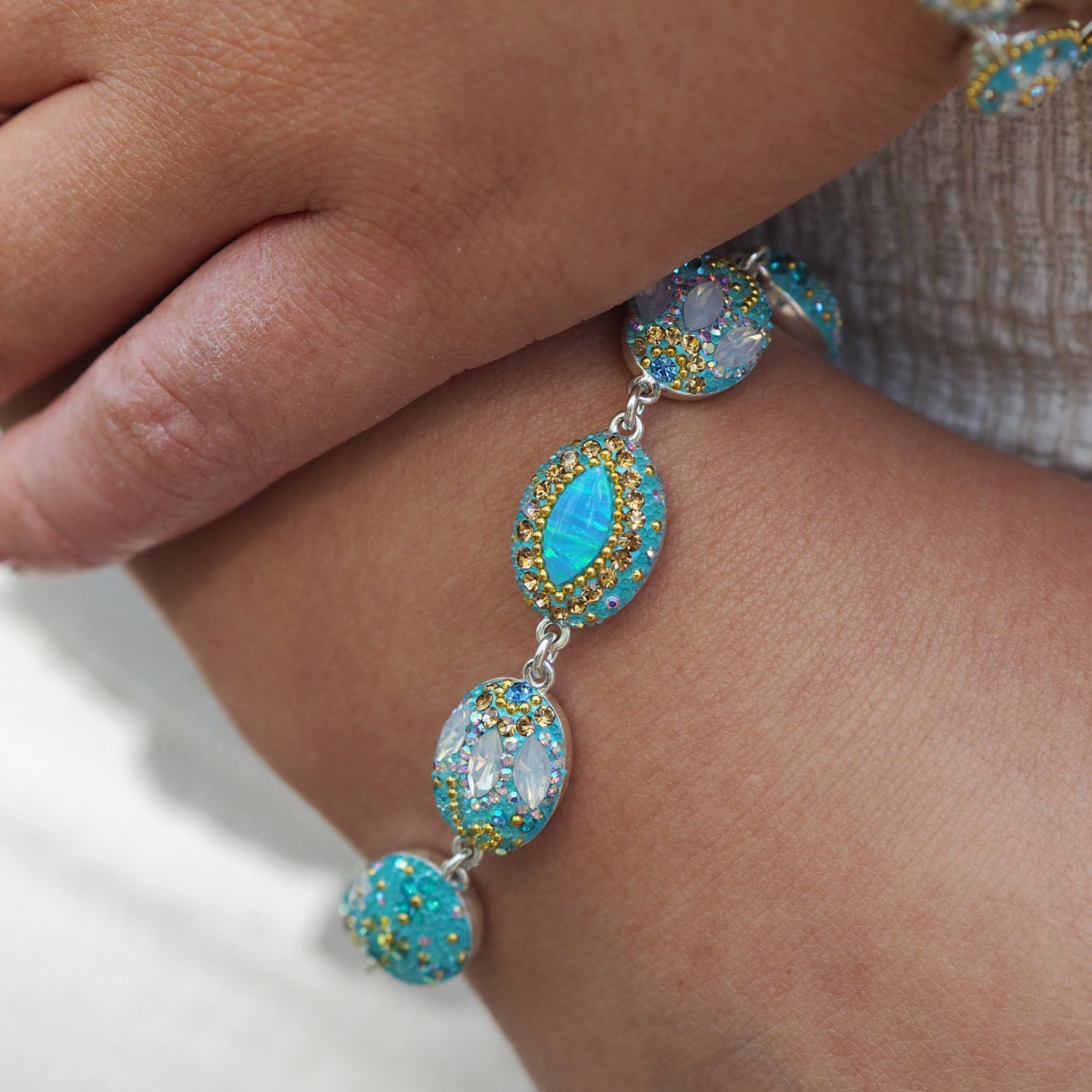Close-up of a turquoise beaded bracelet on a wrist with a neutral background