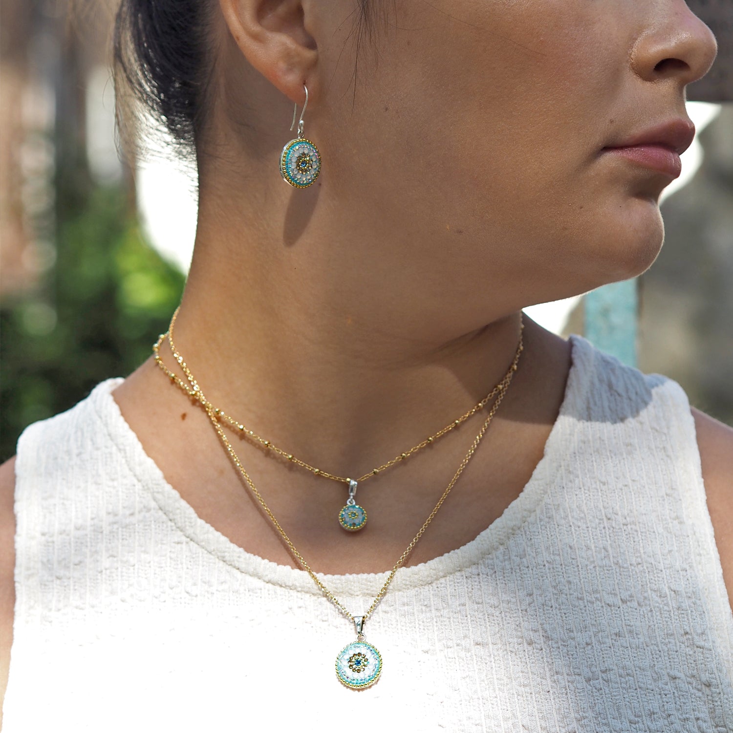 Close-up of a person wearing gold necklaces and earrings with turquoise stones.
