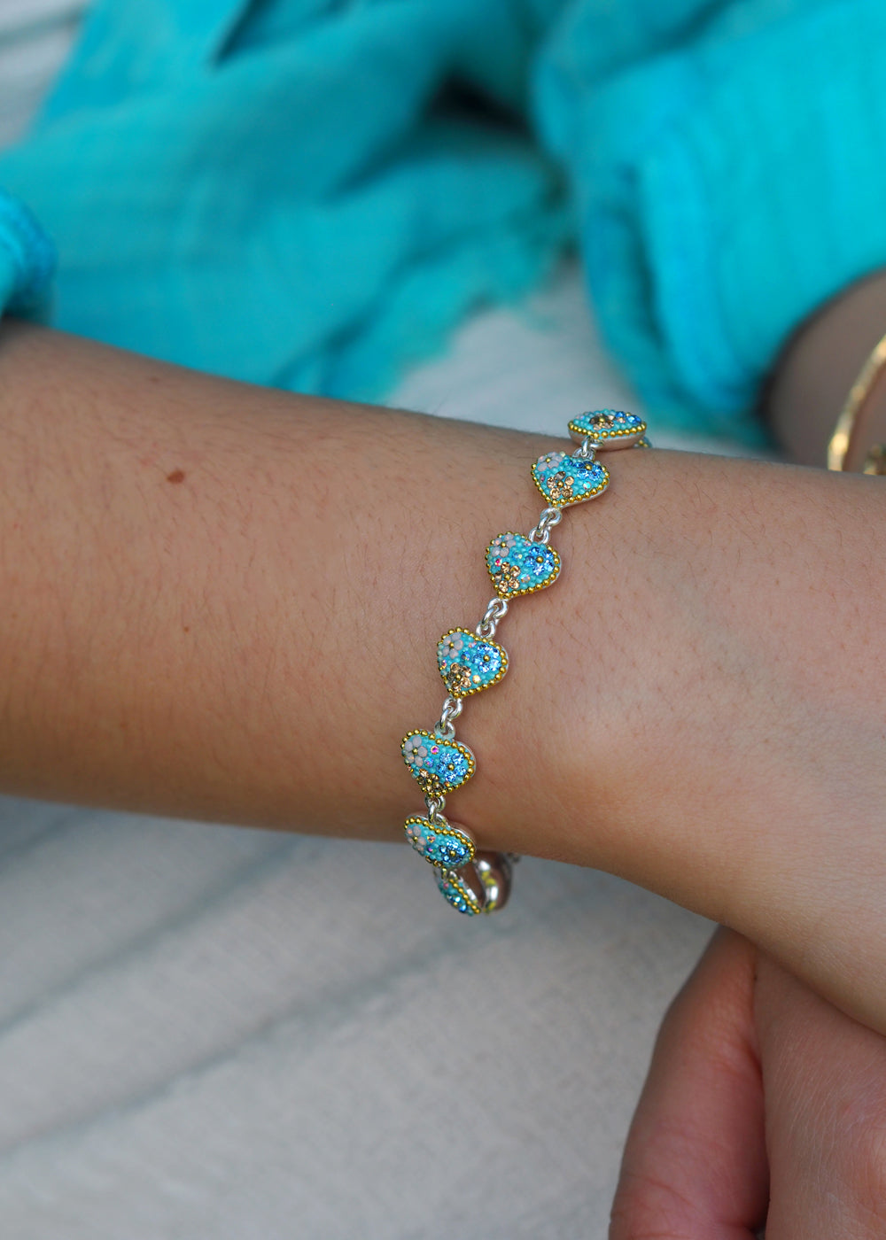 sterling silver heart bracelet worn on wrist teamed with a turquoise shirt