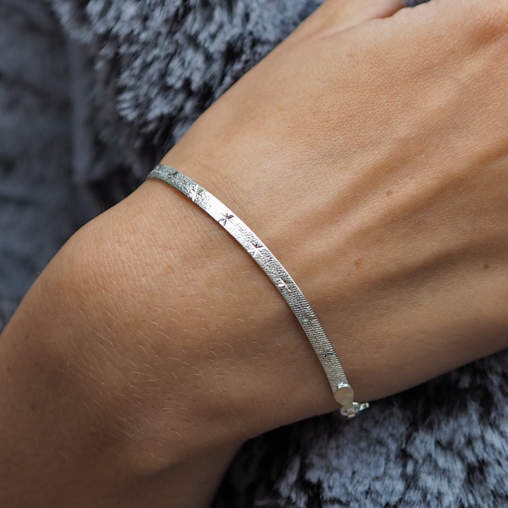 A sterling silver Star Snake Chain bracelet on a person's wrist, displaying the polished facetted stars on herringbone links.