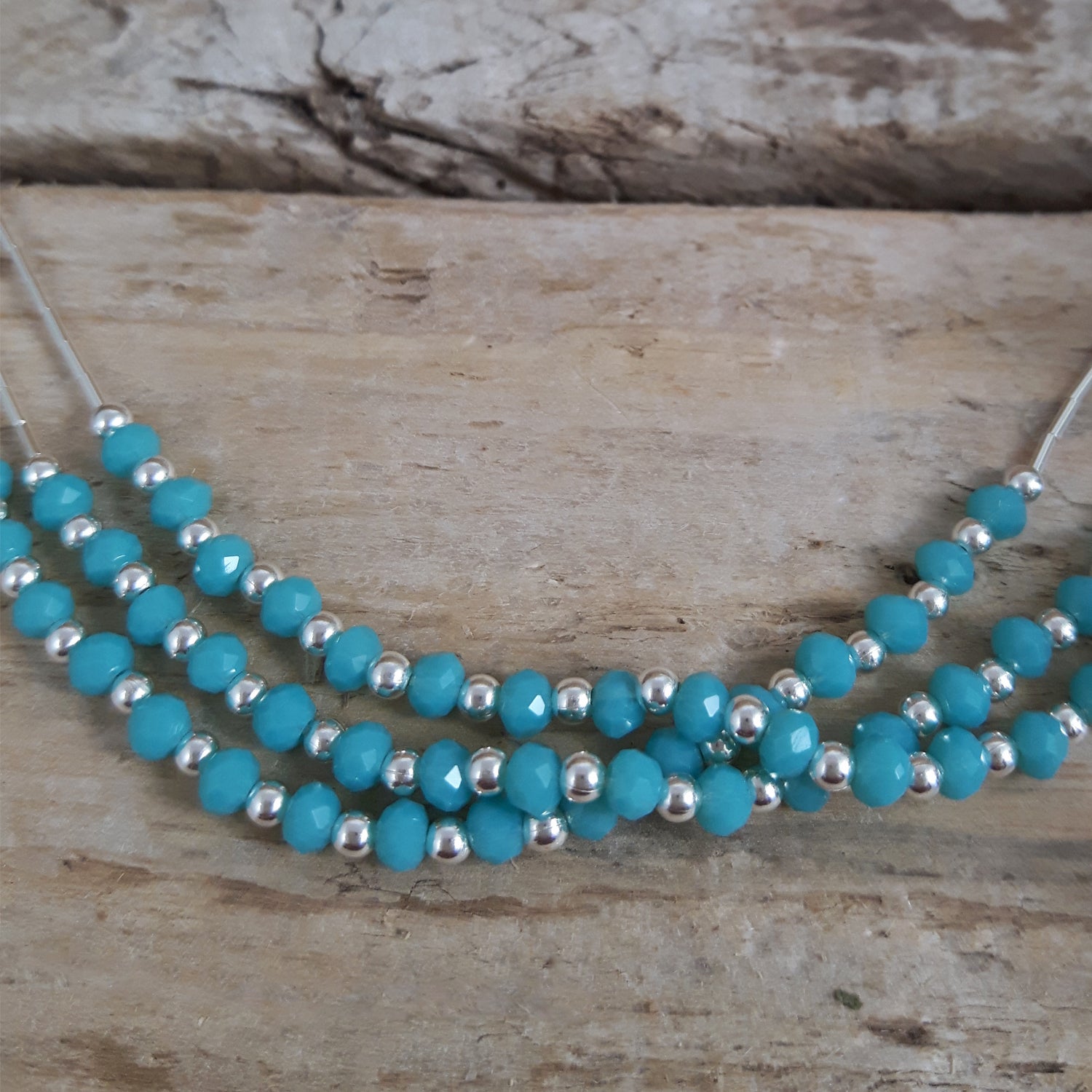 Blue chalcedony beaded necklace with sterling silver accents on a wooden surface