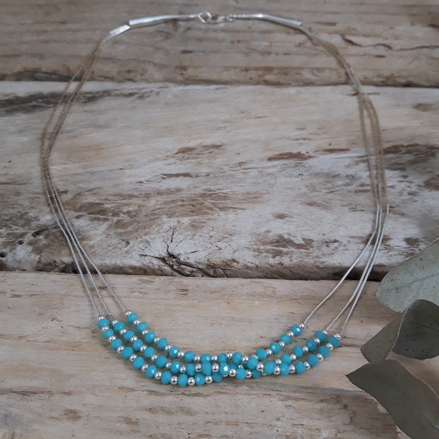 Necklace with blue chalcedony beads and sterling silver accents on a wooden surface