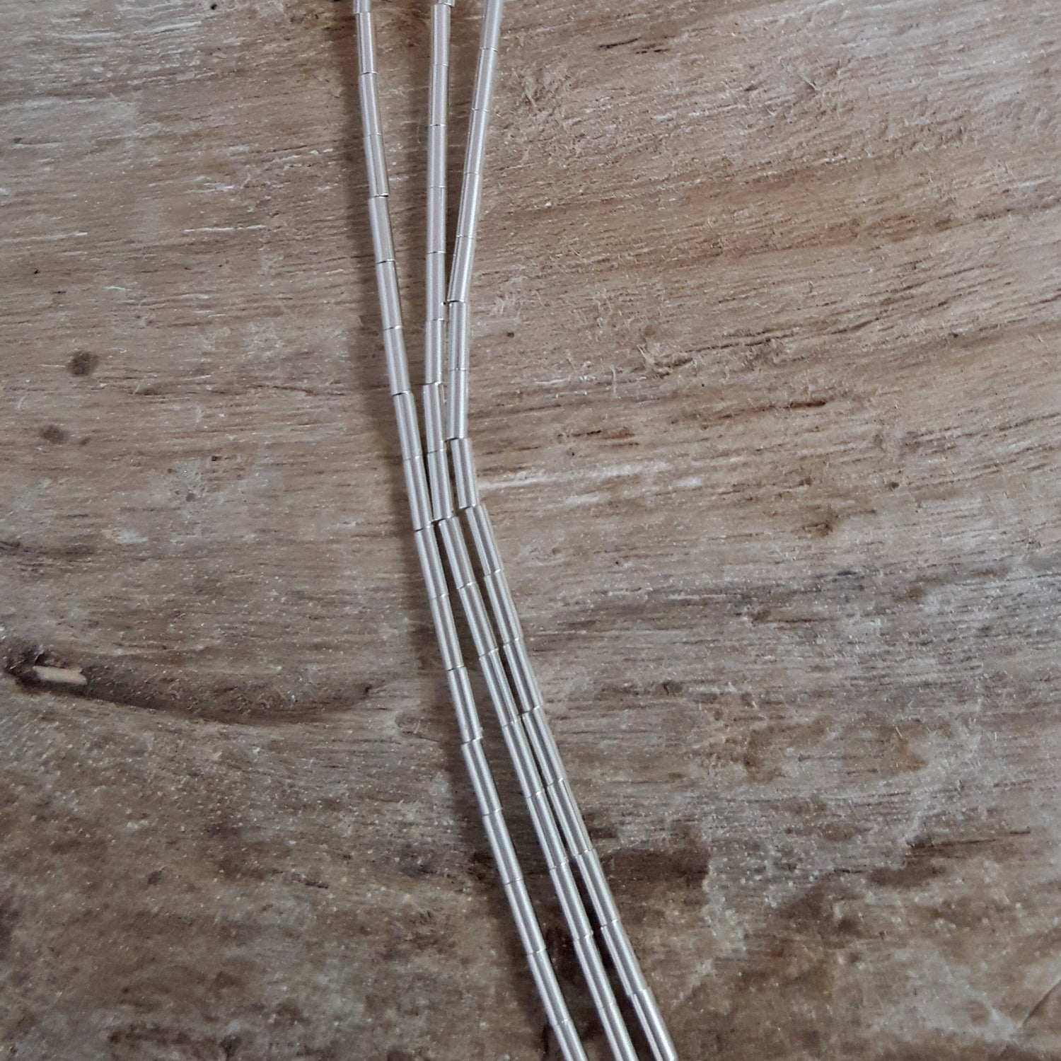 Sterling silver beaded necklace on a wooden surface