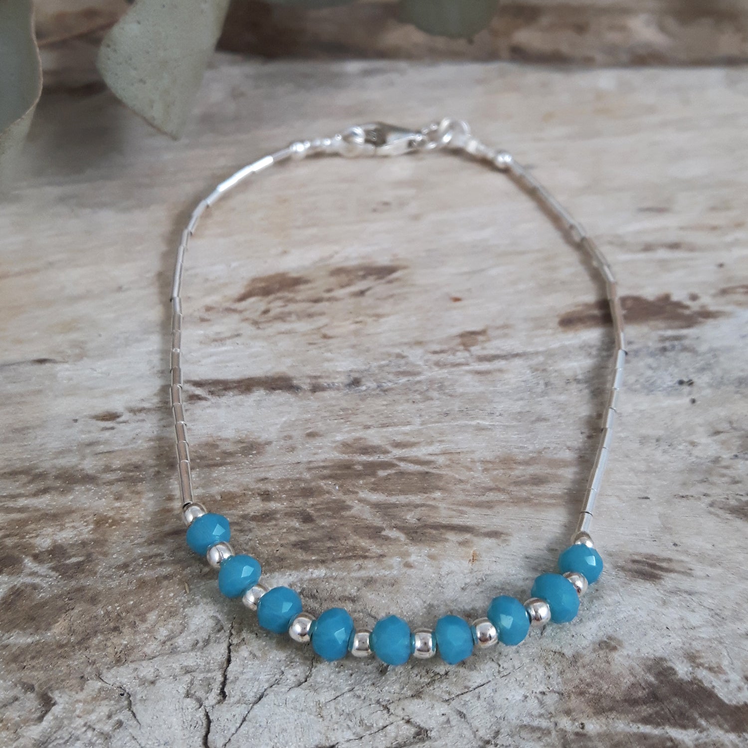 Bracelet with blue chalcedony beads and sterling silver accents on a wooden surface