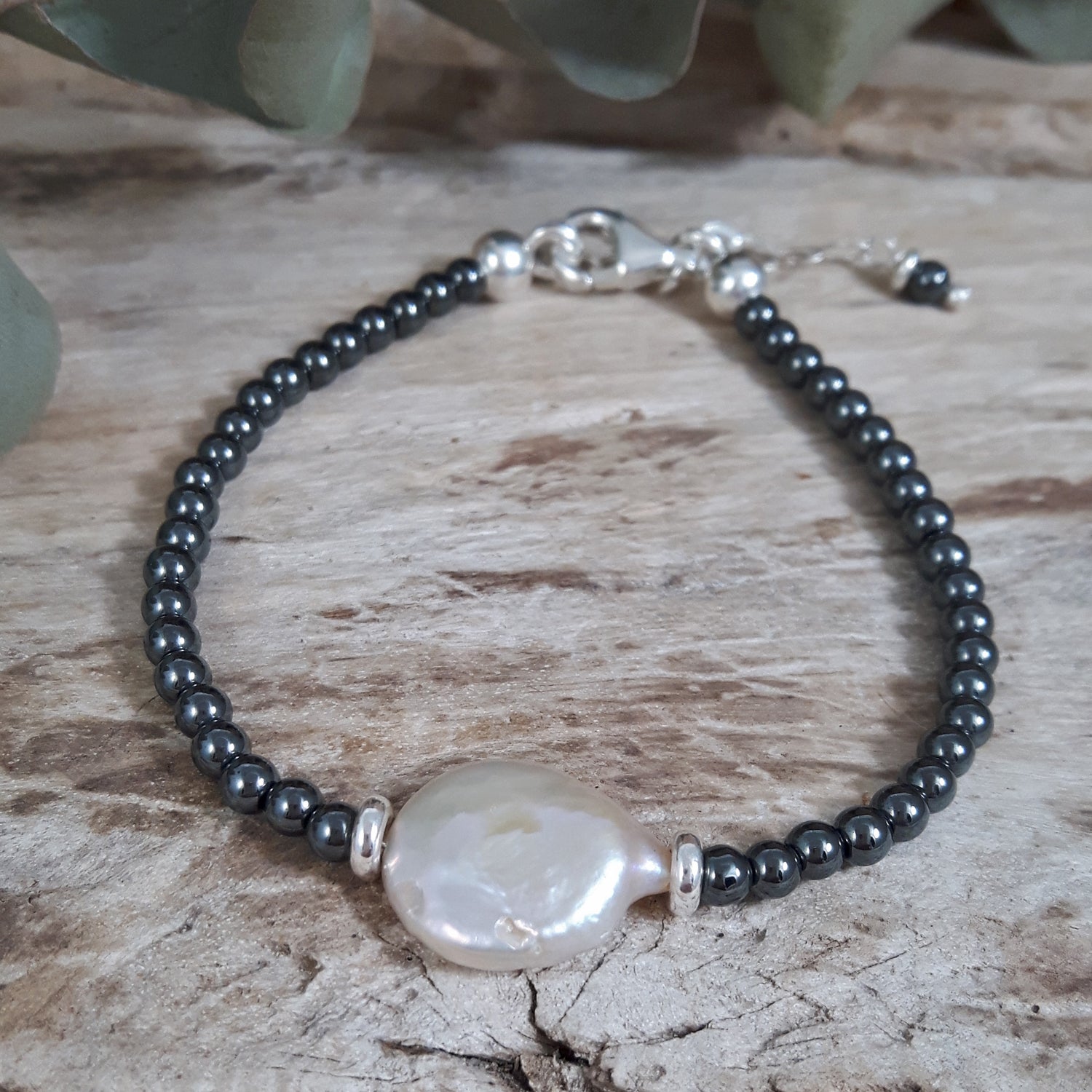 Bracelet with hematite beads and a large pearl on a wooden surface, handcrafted in Mexico, UK gift