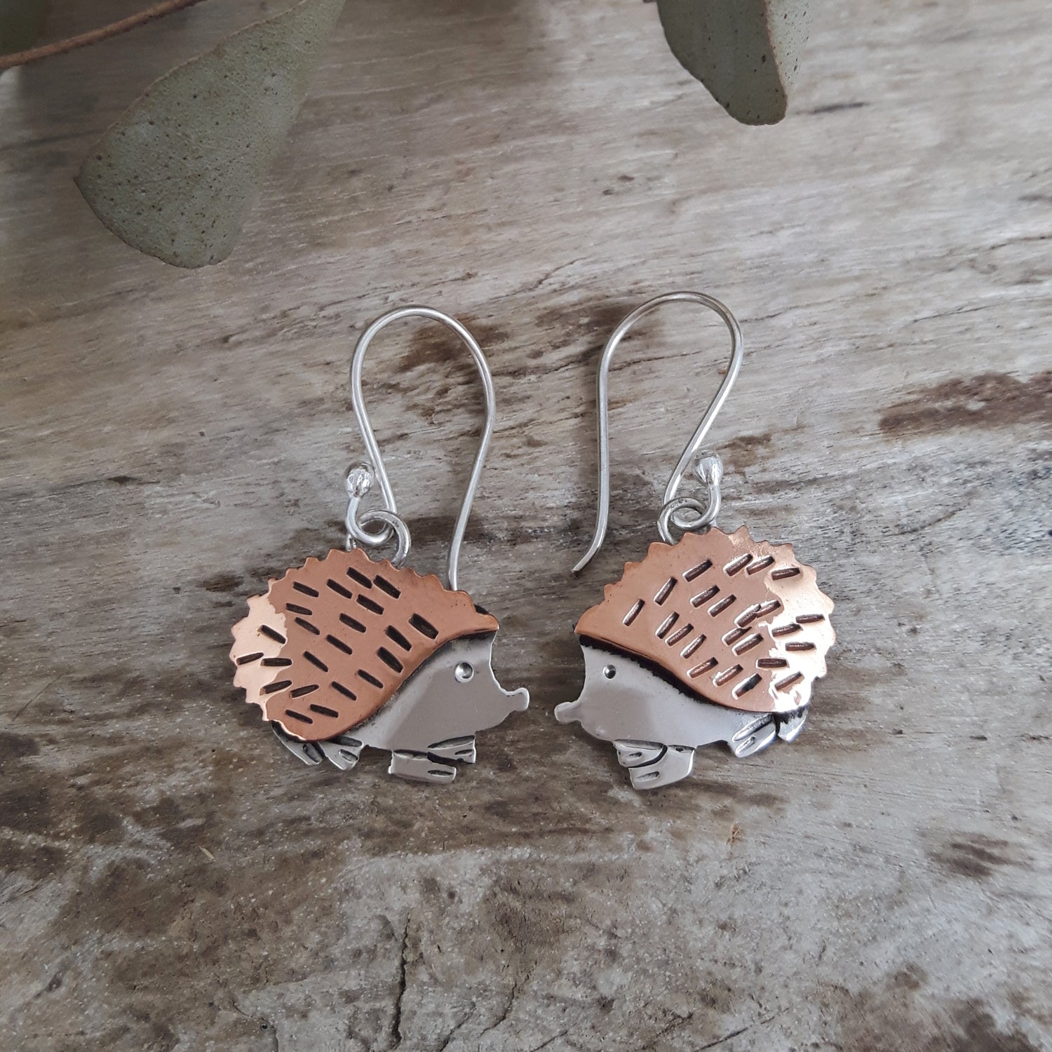 Handcrafted hedgehog-shaped drop earrings on a wooden surface