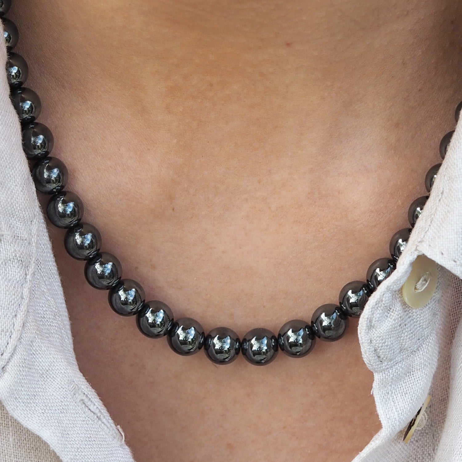 Woman wearing a beaded hematite necklace with a white shirt. Gifts under £100