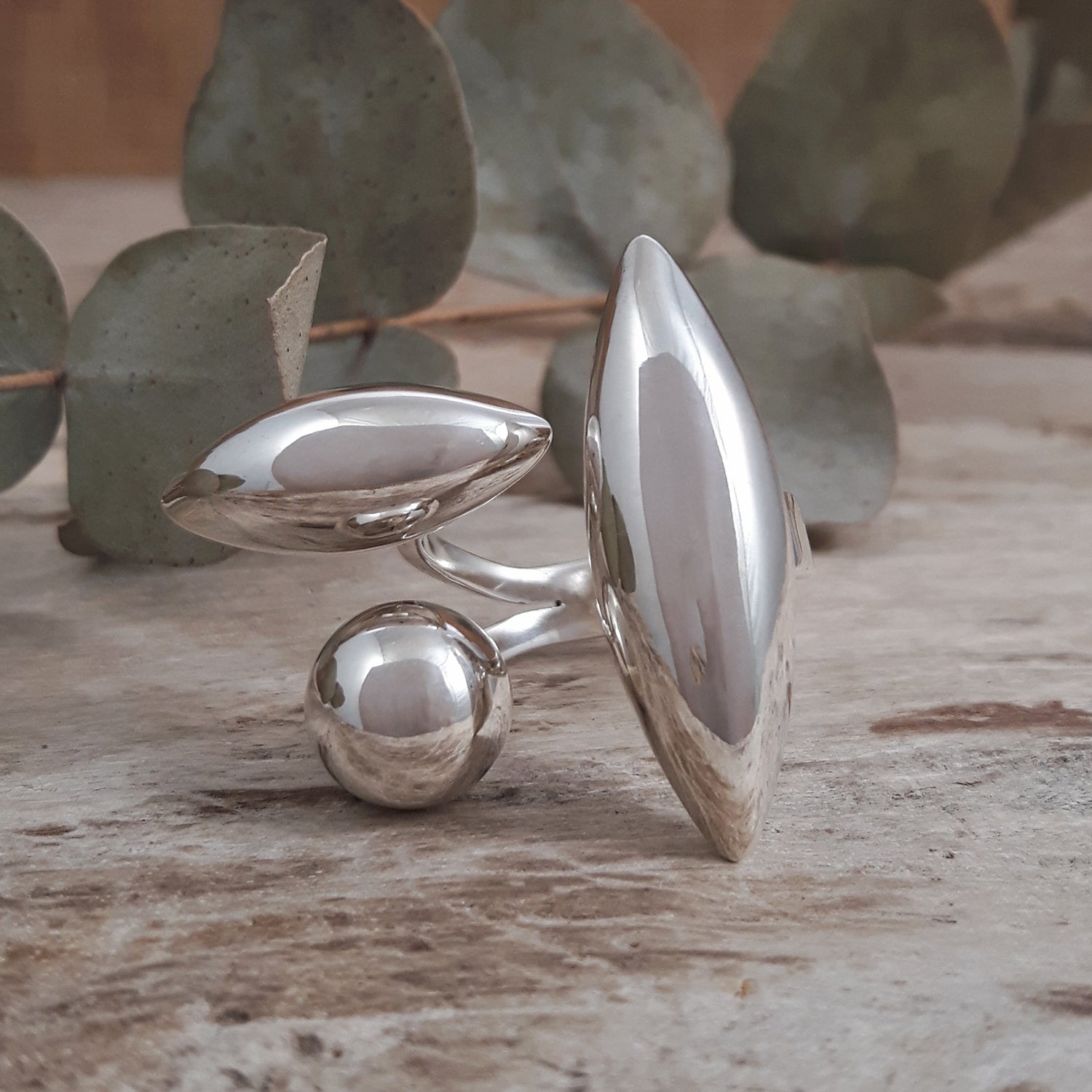 Polished 925 sterling silver ring with geometric design on a wooden surface with leaves in the background