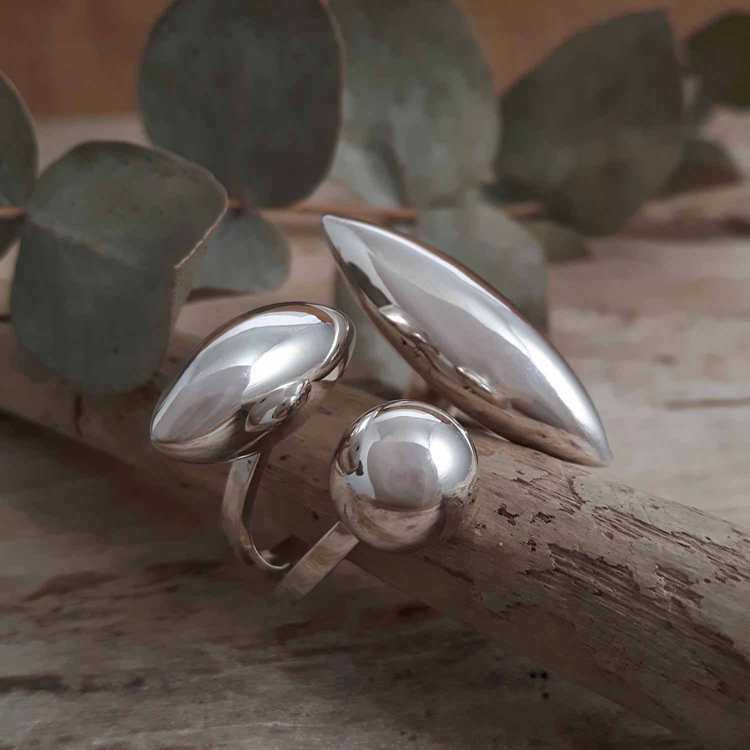 Sterling silver ring with a unique design on a wooden surface with leaves in the background