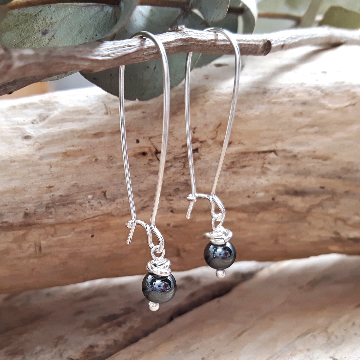 Artisan sterling silver earrings with hematite beads hanging on a branch