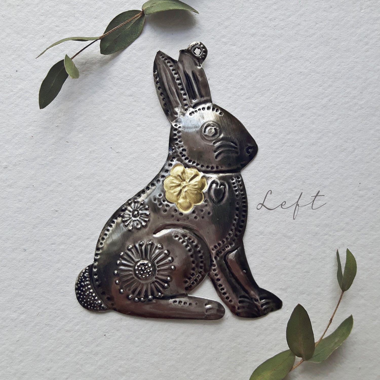 Decorative metal rabbit sculpture with gold accent on a textured white background