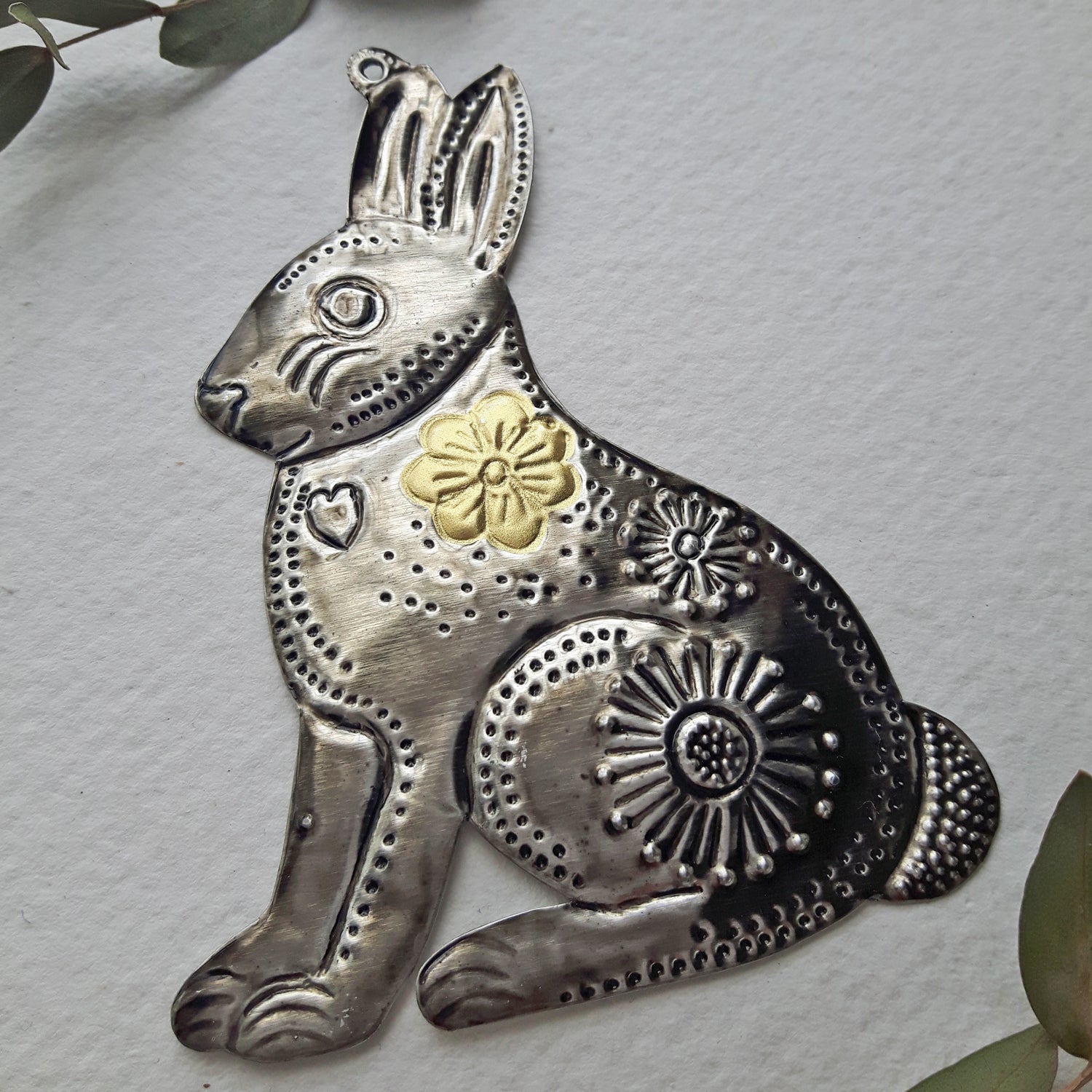 Decorative metal rabbit ornament with floral designs on a light gray background