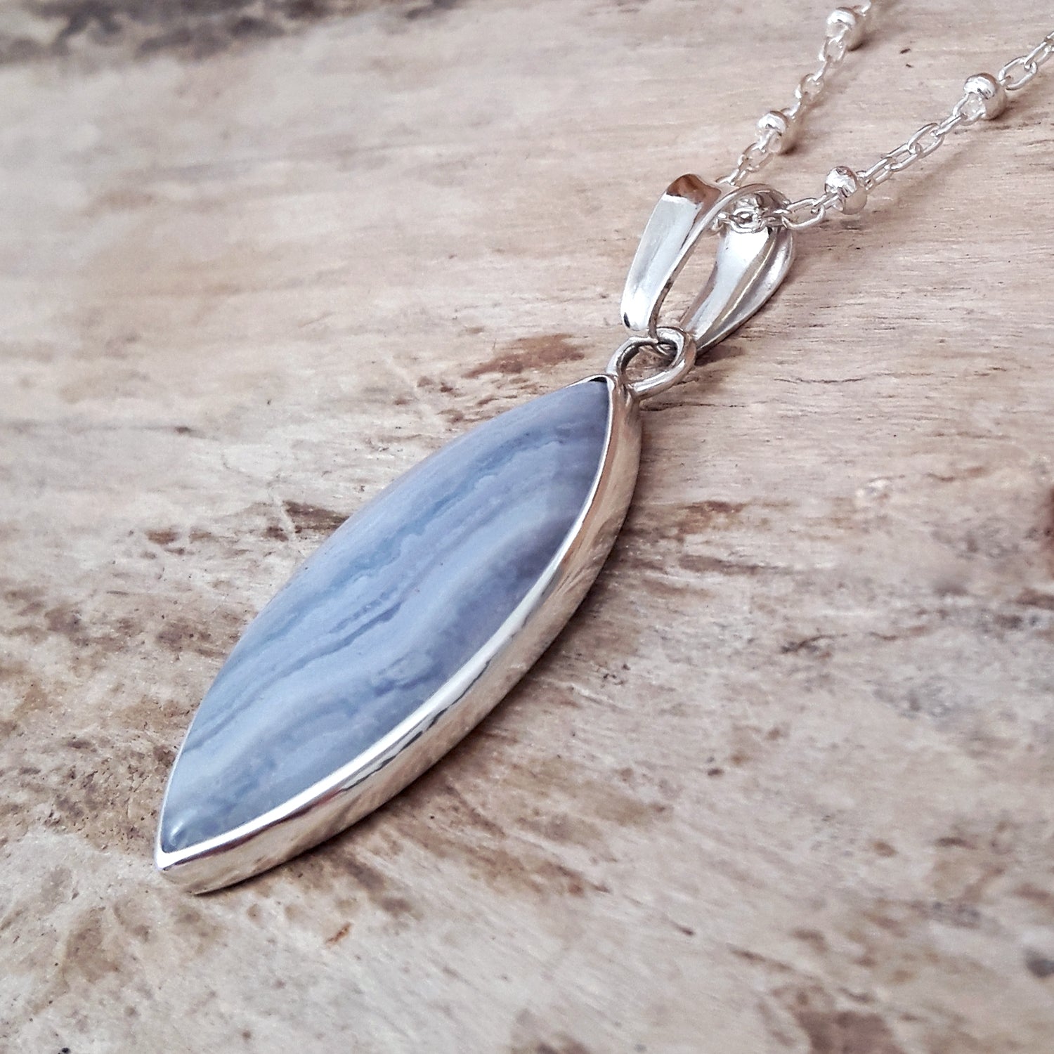 Sterling silver pendant with a blue lace agate stone on a wooden surface