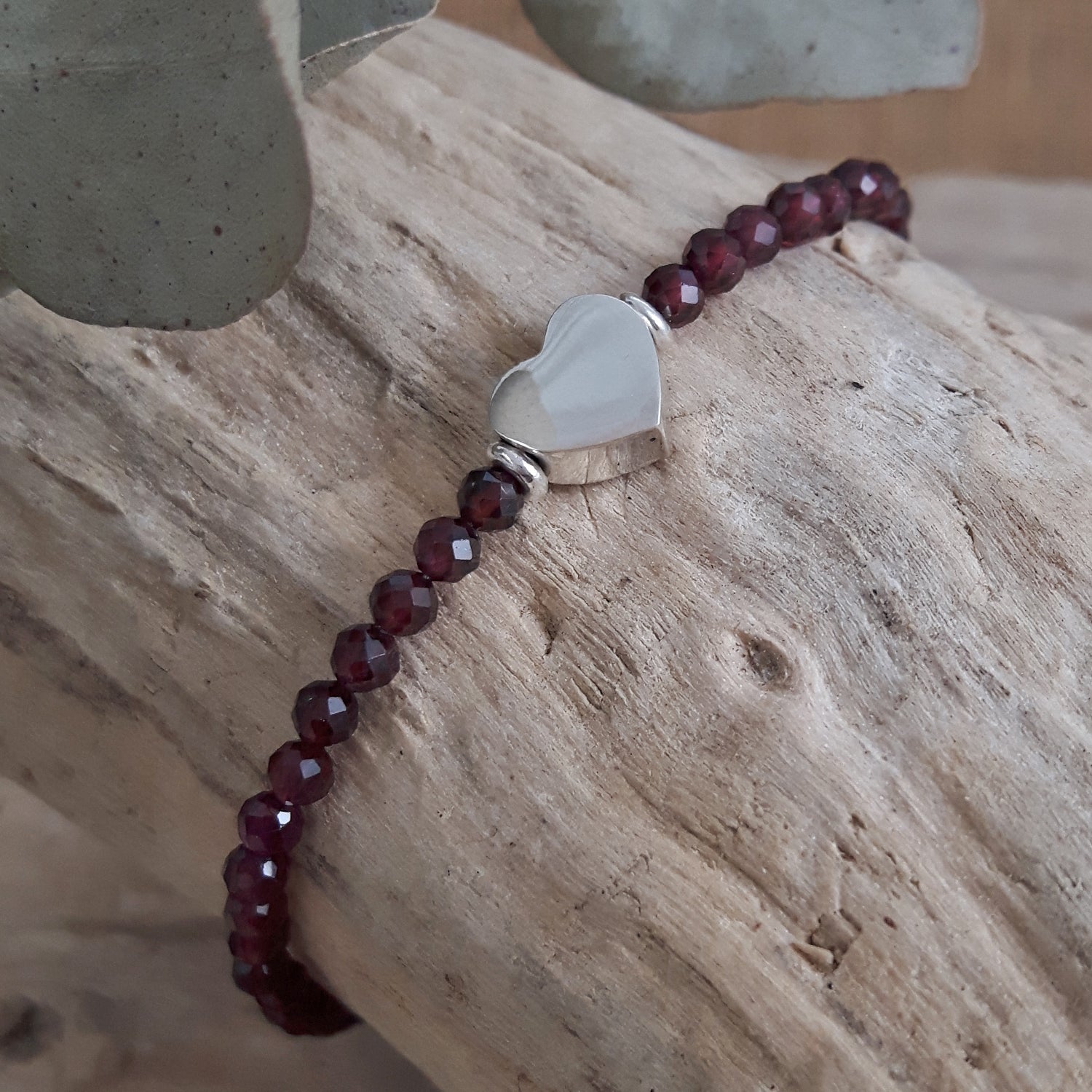 Garnet beaded bracelet with a heart-shaped clasp on a wooden surface