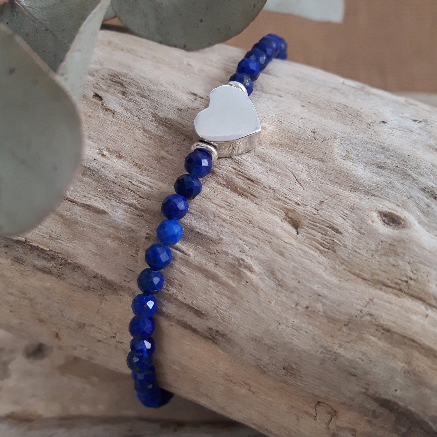 Blue Lapis beaded bracelet with a sterling silver heart charm on a wooden surface