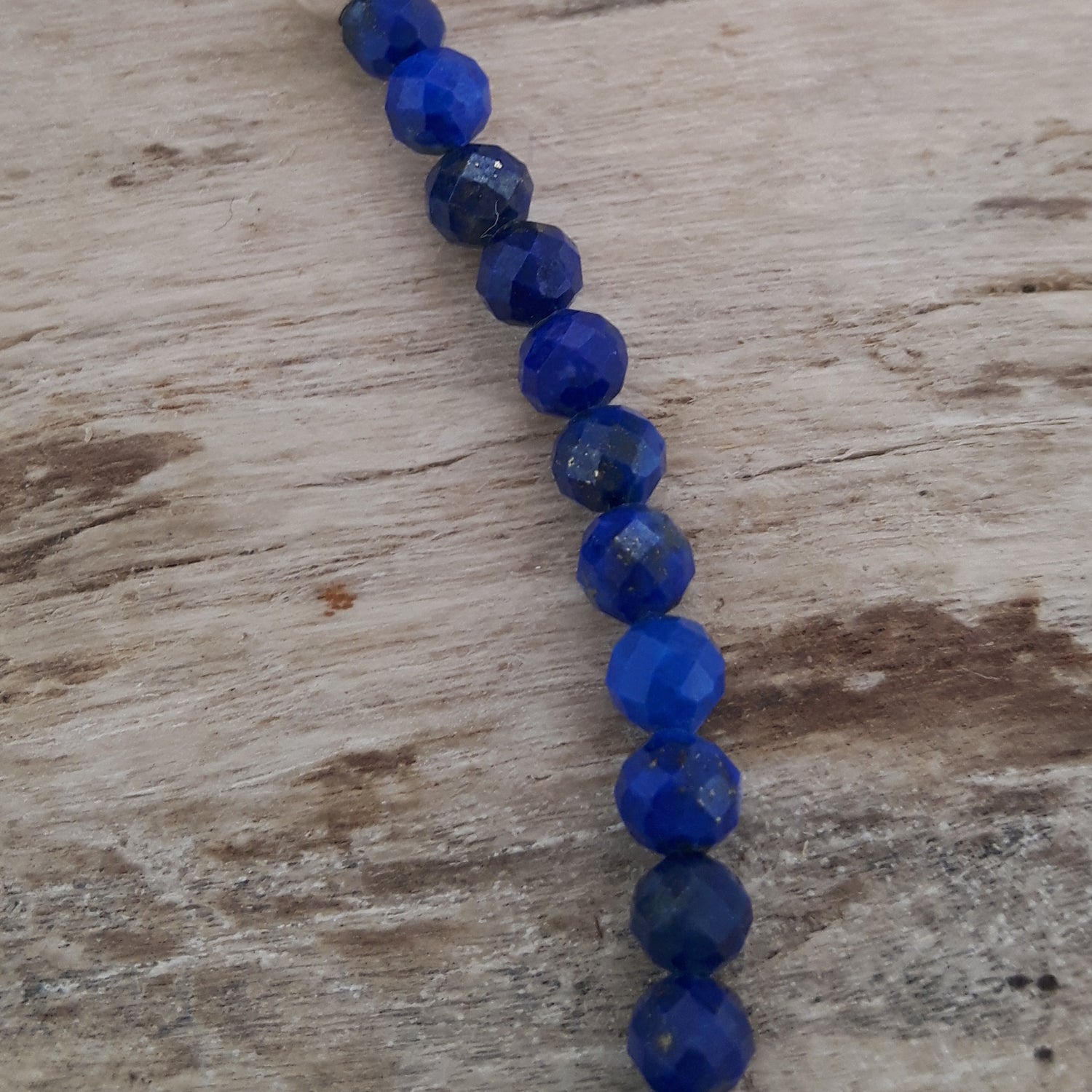 String of blue lapis beads on a wooden surface