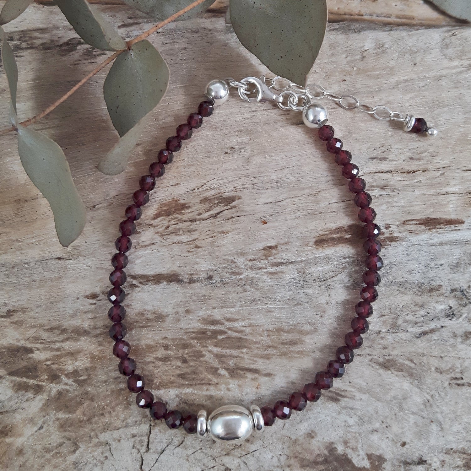 Garnet beaded bracelet with silver accents on a wooden surface