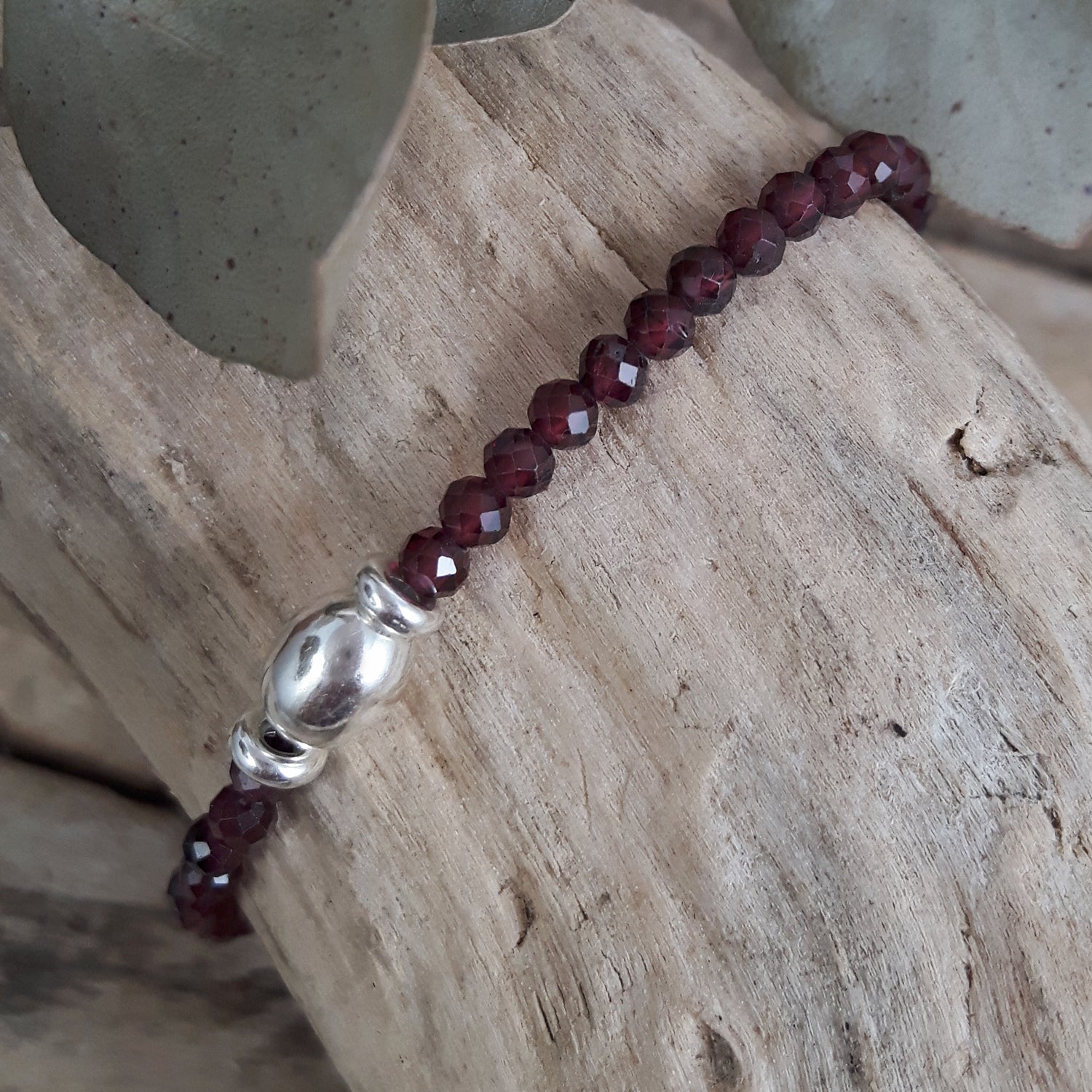 Garnet beaded bracelet with a silver clasp on a wooden surface