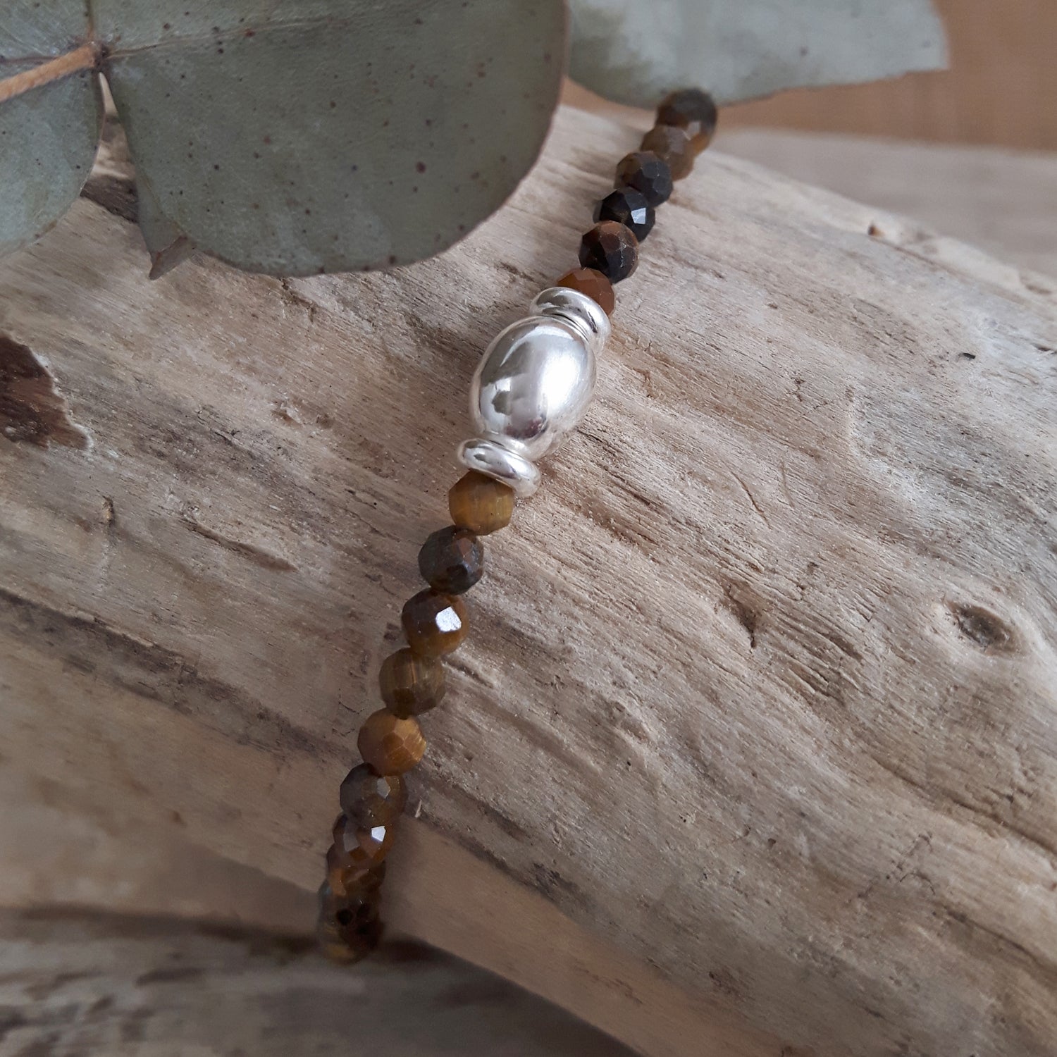 Tiger's Eye beaded gemstone bracelet with sterling silver focal bead on a wooden surface