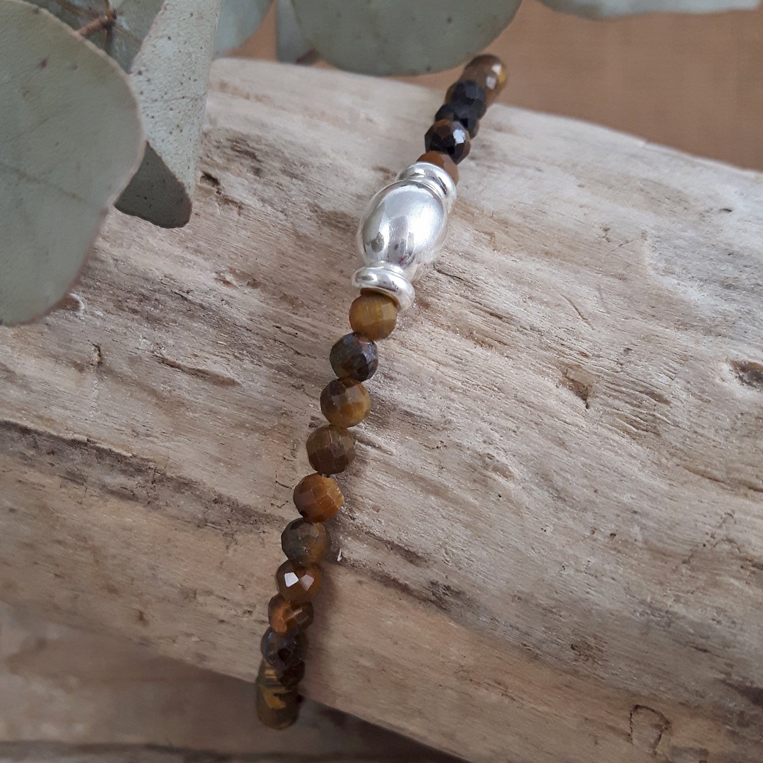 Tiger's Eye beaded bracelet with a silver central bead on a wooden surface
