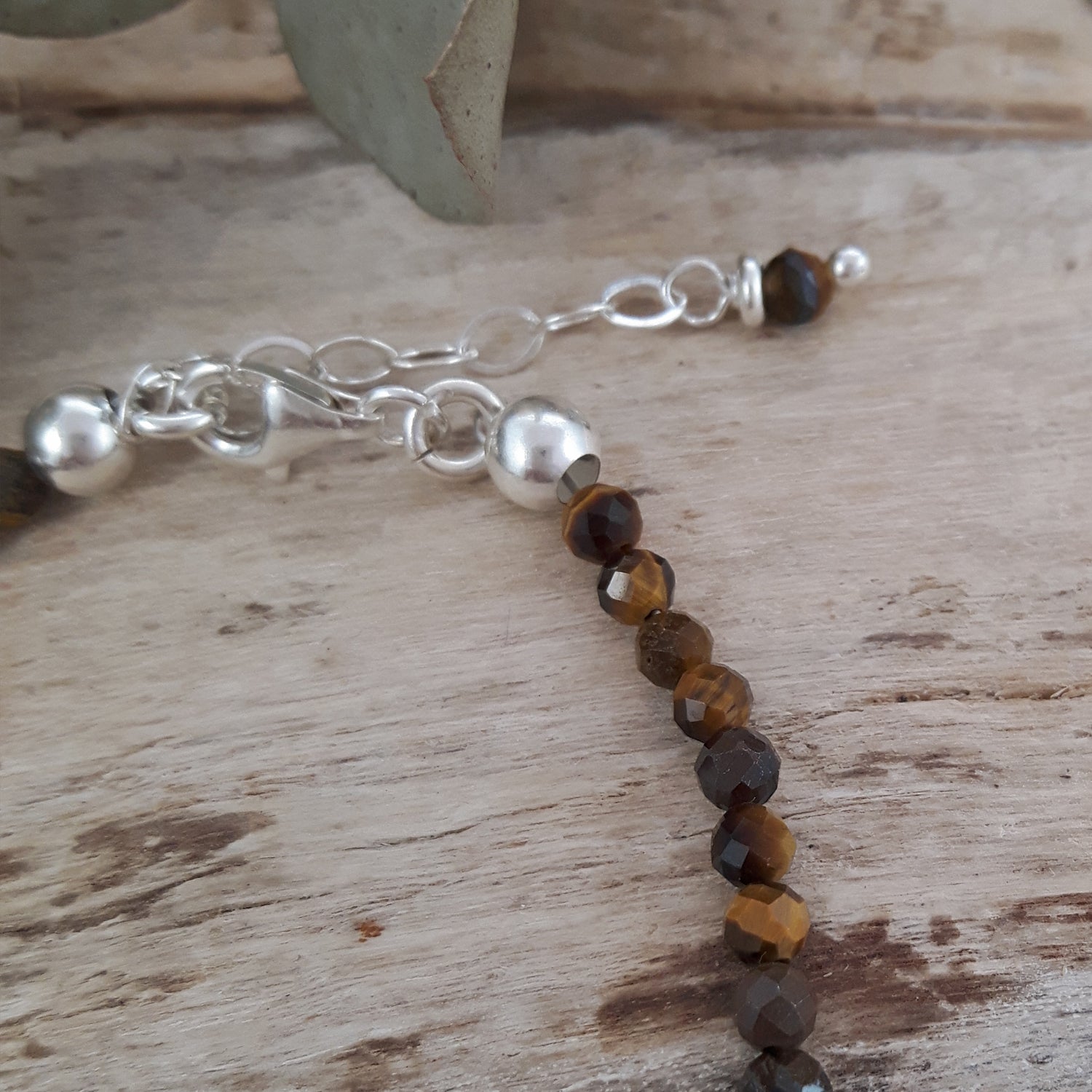 Tiger's Eye bracelet with silver and brown beads on a wooden surface
