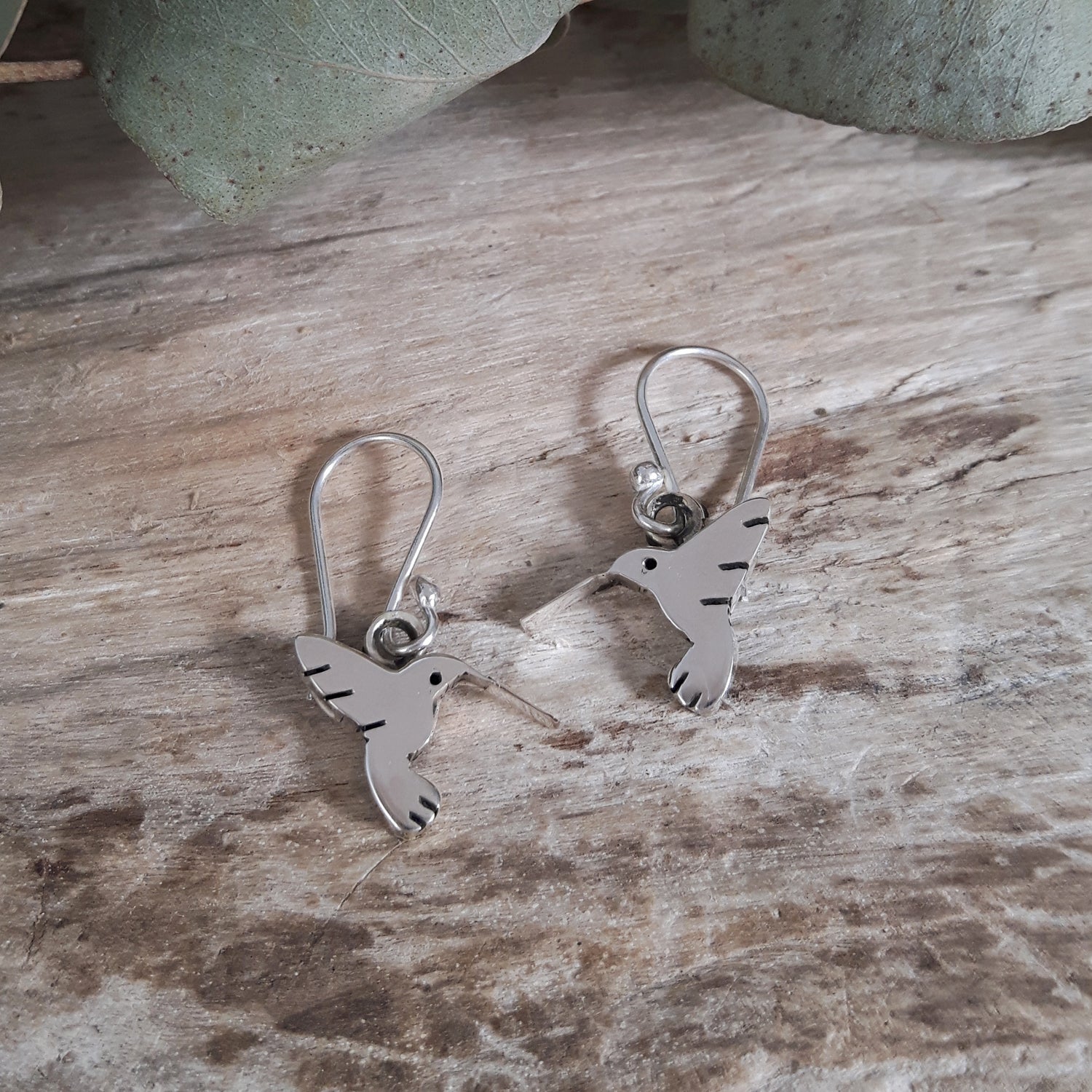 Lightweight sterling silver hummingbird drop earrings worn on ear