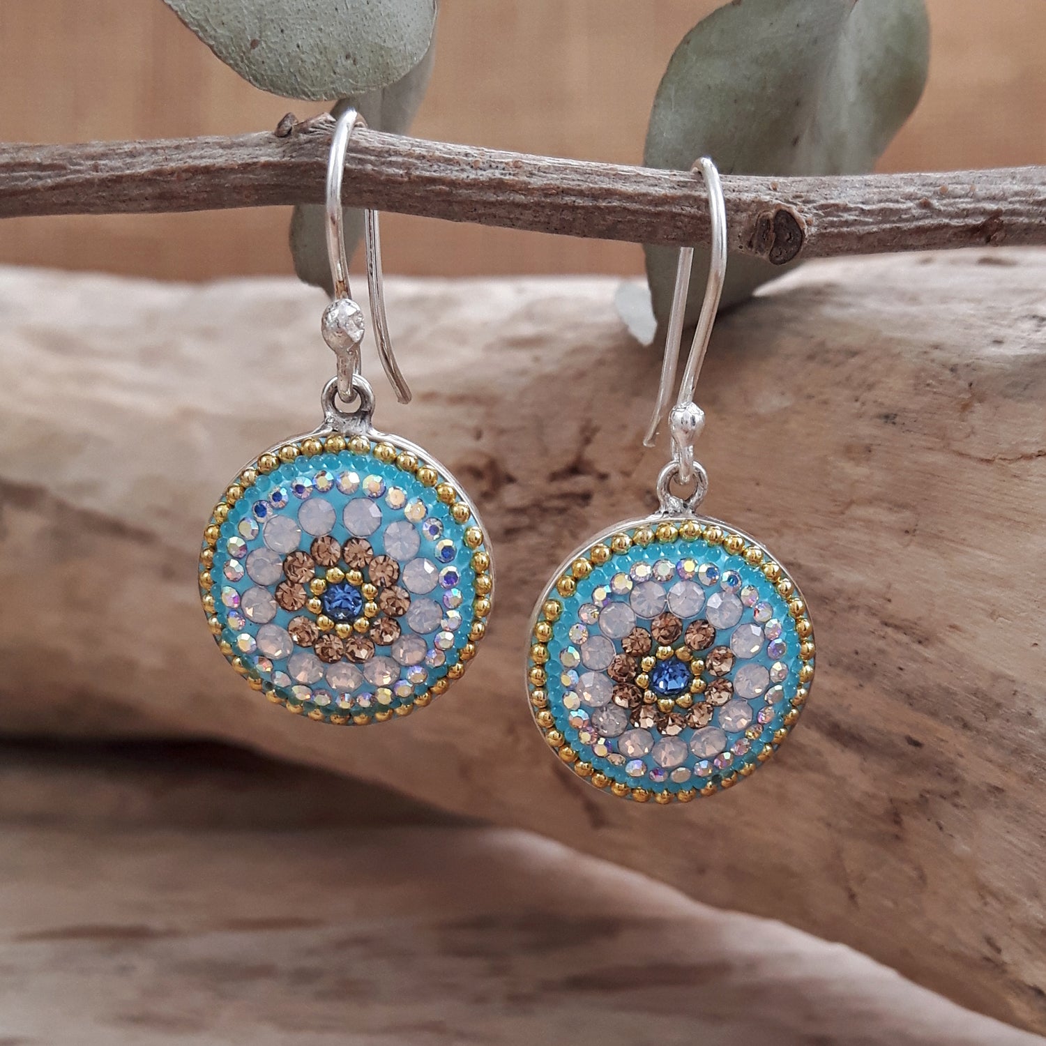 A pair of sterling silver drop earrings with floral patterns, featuring a mix of clear, turquoise, and aqua crystals.