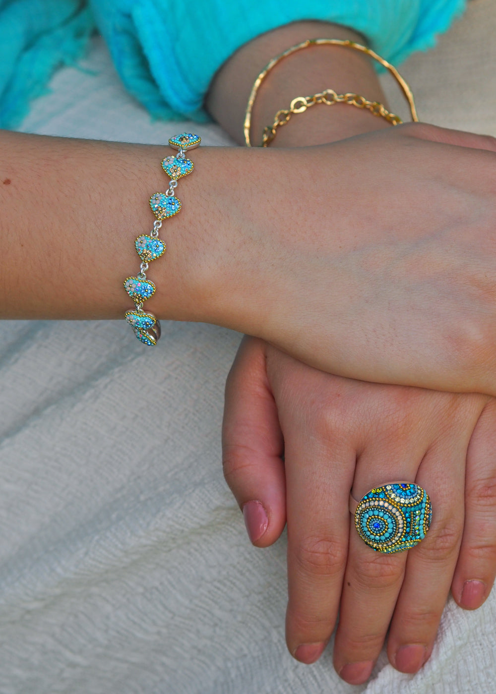 sterling silver heart bracelet worn with statement ring and gold bracelets